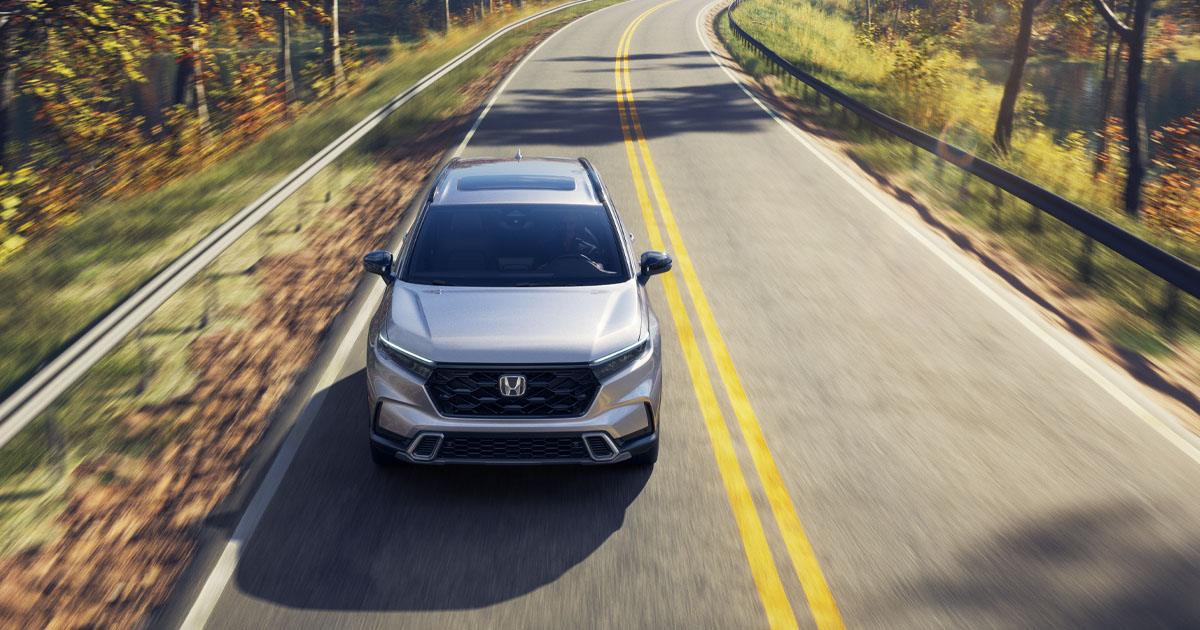 Honda CR-V Sport Touring Hybrid in Solar Silver Metallic driving down the highway