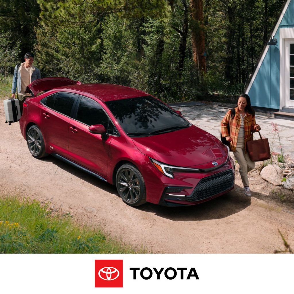 2024 Corolla Hybrid parked in front of a cabin with one person opening the trunk