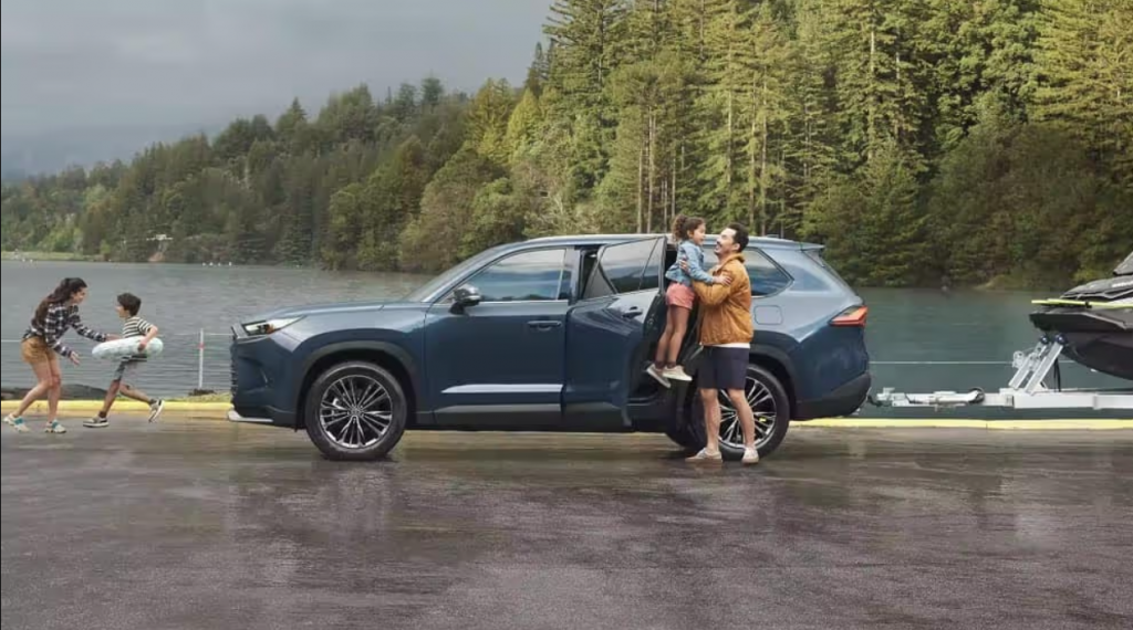 A father lifts his young daughter in the air happily as he prepares to load her into her seat of a Toyota SUV.