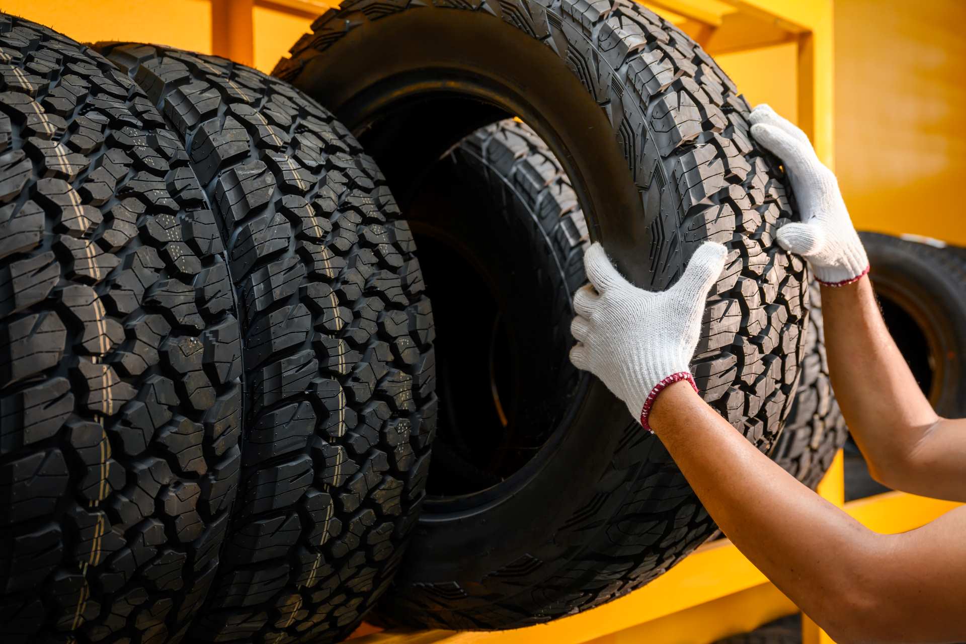 a truck services employee wearing shop gloves pulling oversized aftermarket tires off a shelf