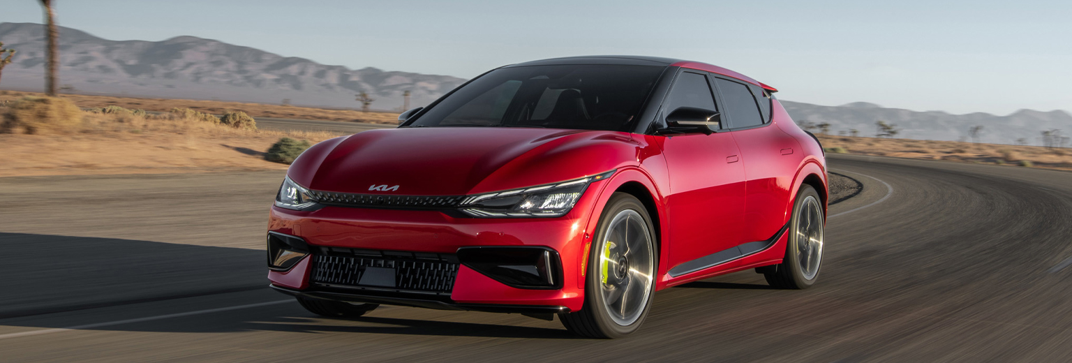 2023 Blue Kia EV6 GT vehicle driving down an open road in the desert