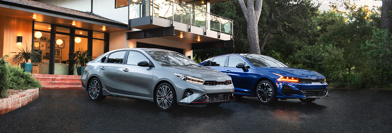 2022 Kia Forte and 2022 Kia K5 GT vehicles in the driveway of a home in a suburb