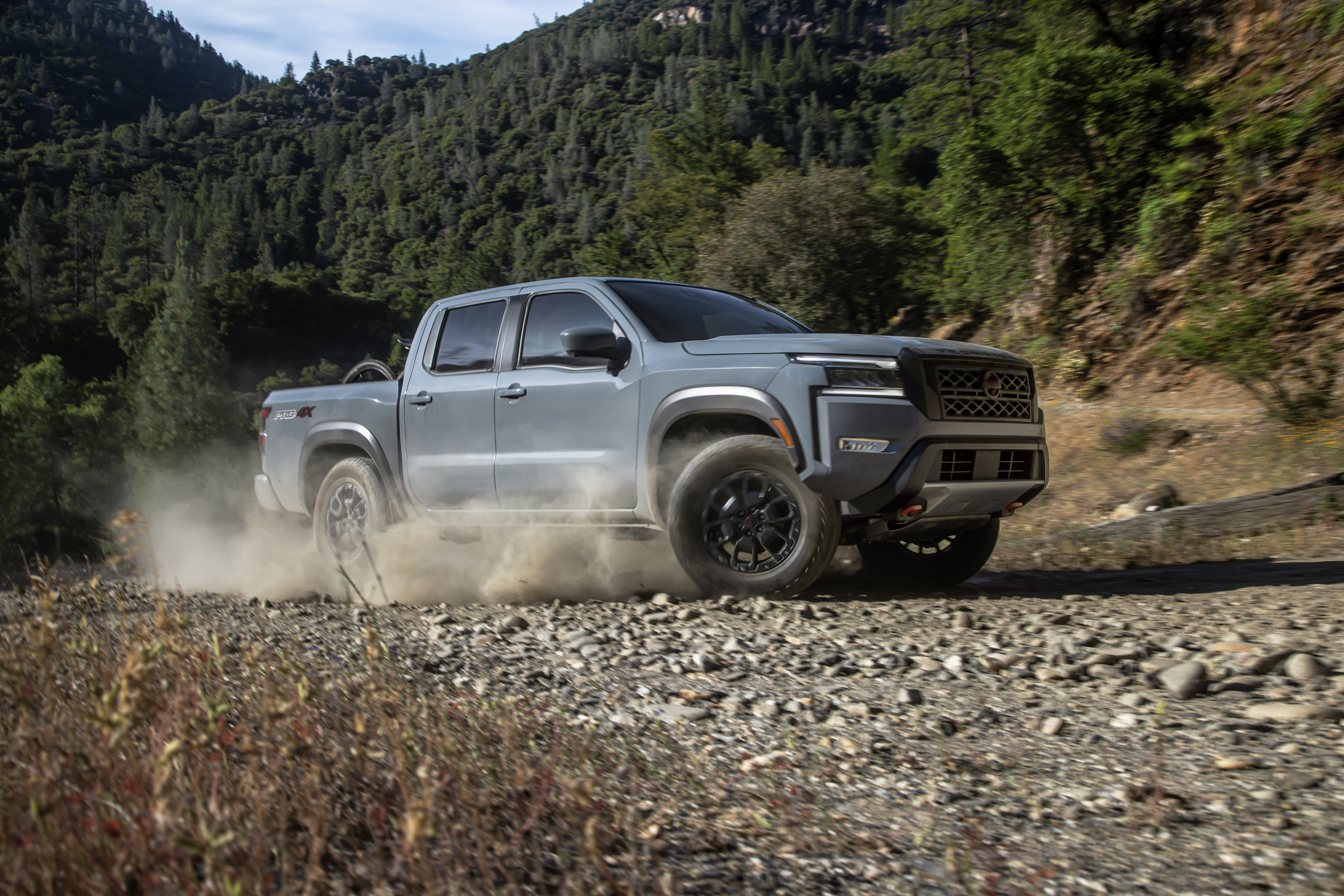 Nissan Frontier driving through dirt in a mountain area