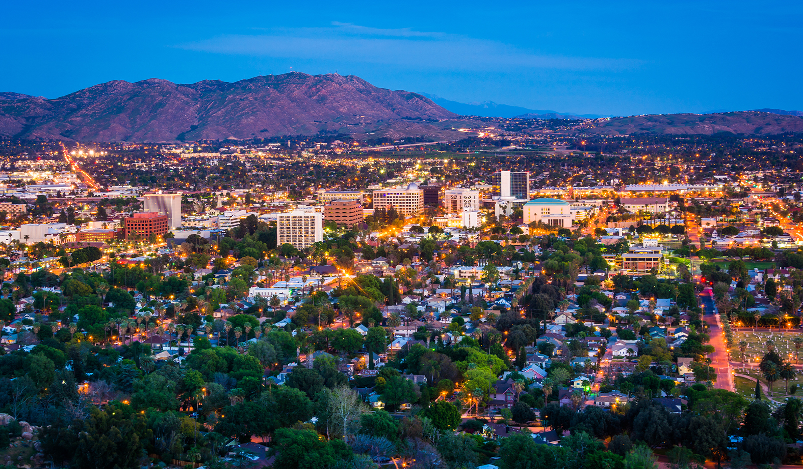 Aerial view of a city with mountains and a blue sky in the background