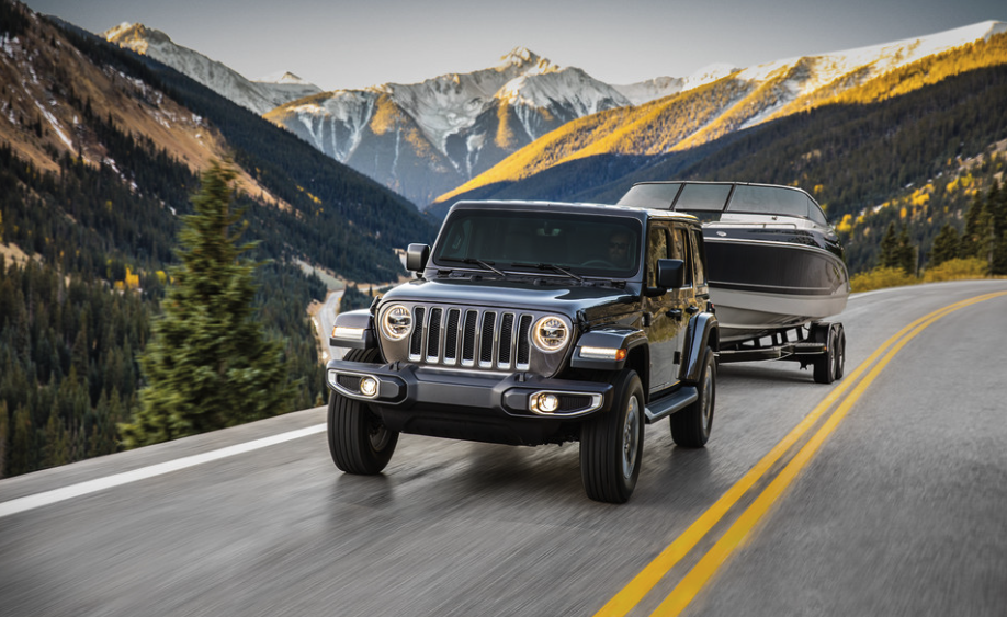 Jeep Wrangler Towing a Boat driving through a mountainous road