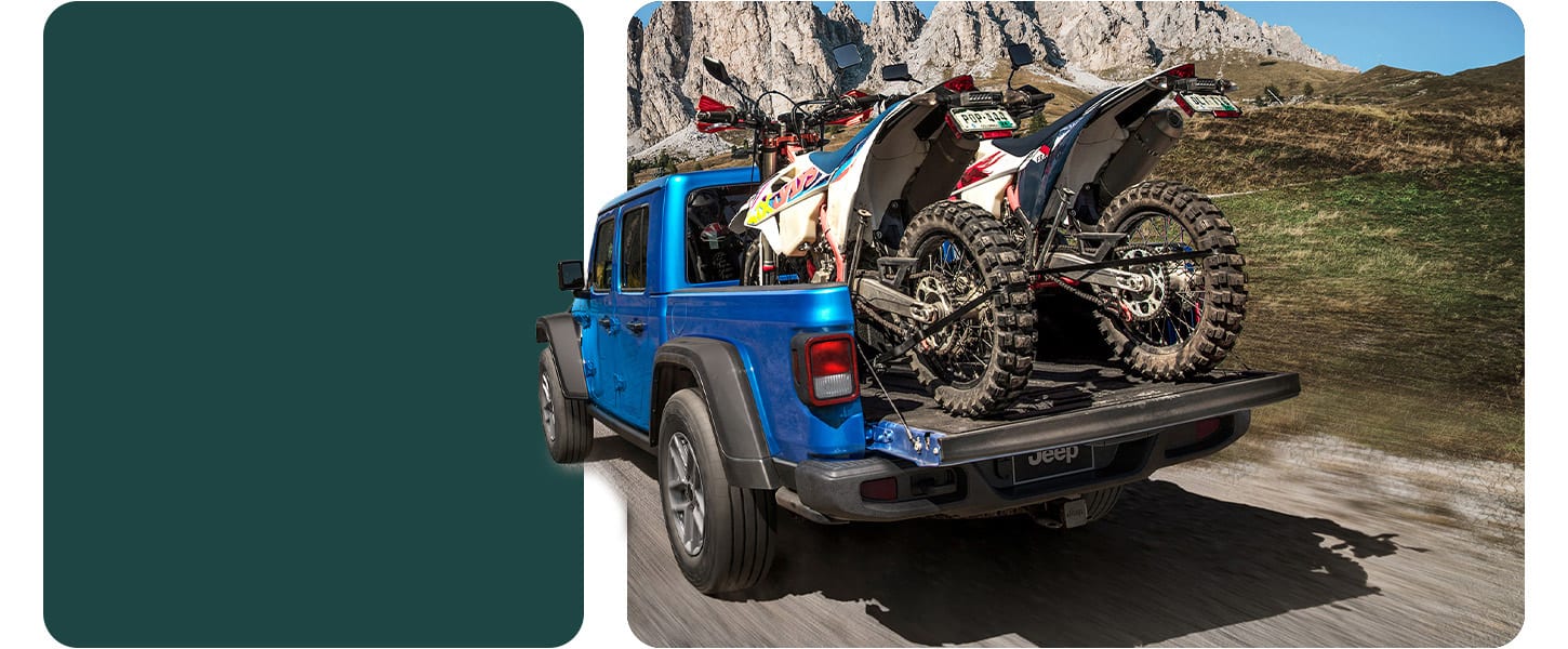 2026 Jeep Gladiator hauling dirt bikes in the cargo bed on a mountain trail