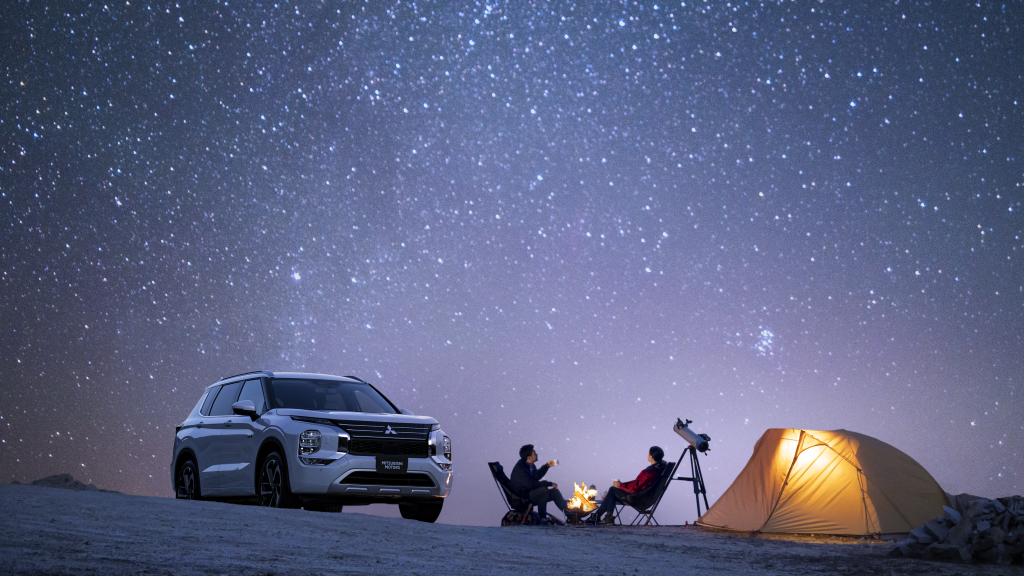 2024 Outlander PHEV SE parked at a campground under the night sky