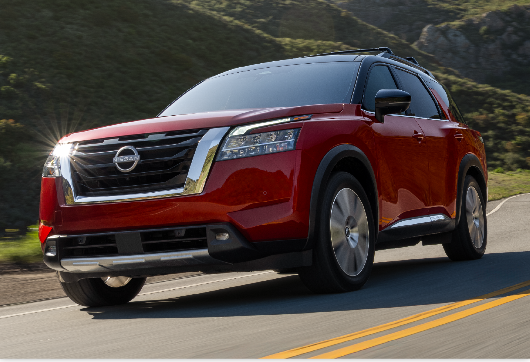 Red Nissan Pathfinder driving on a mountain road