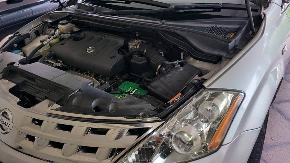 The engine of a grey Nissan car.