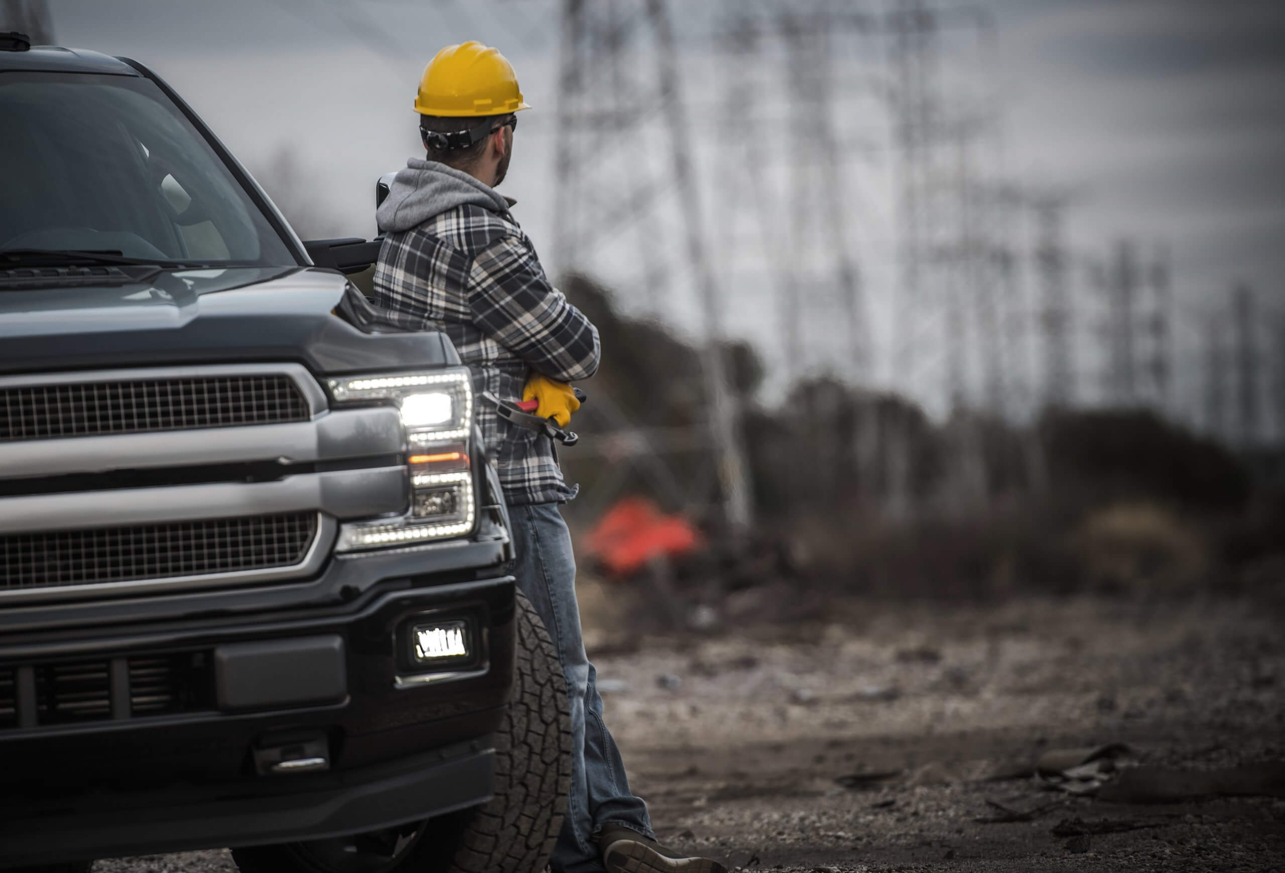 Man at job site leaning on a work truck