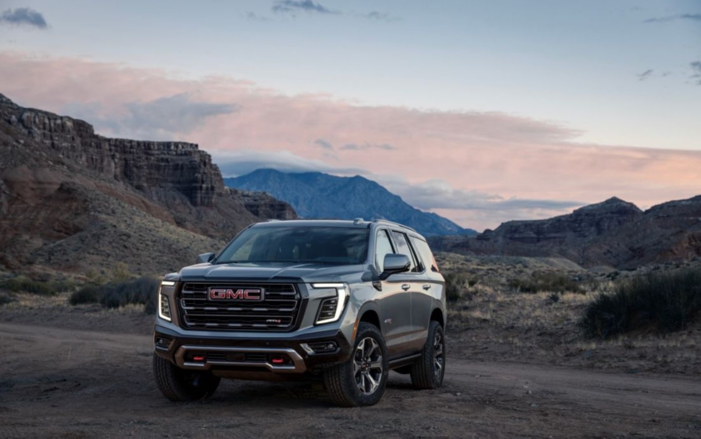 3/4 profile of a new GMC Yukon parked on a rough dirt road at sunset 