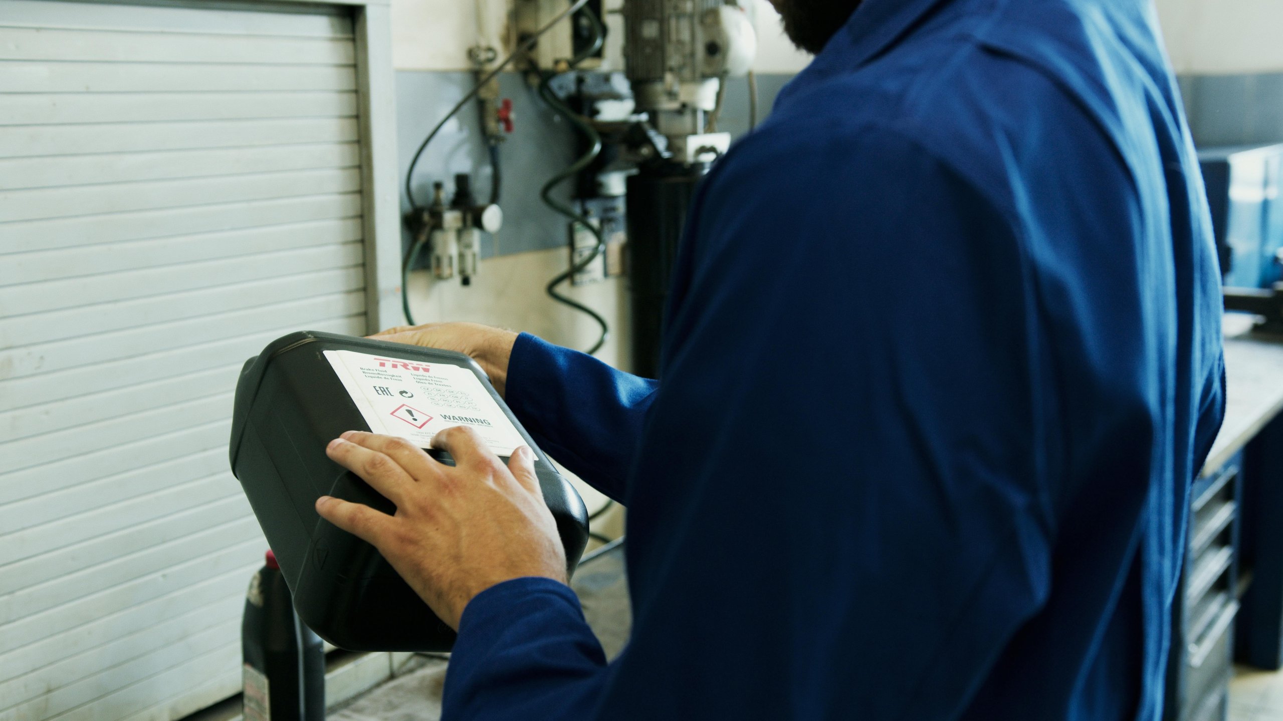 A mechanic examining the label on a bottle of engine oil