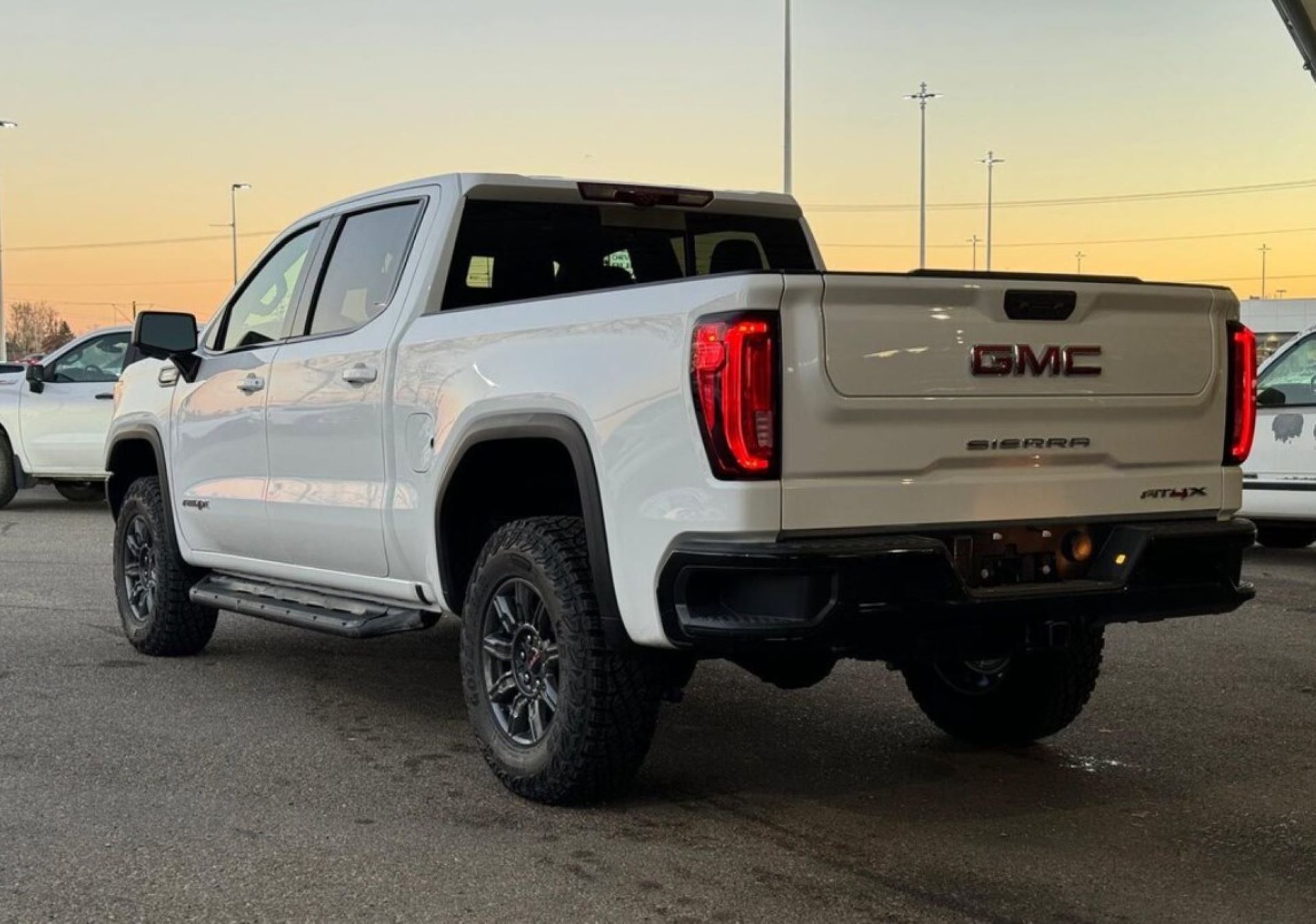 a new white GMC Sierra 1500 AT4X leaving a parking lot after snow melt
