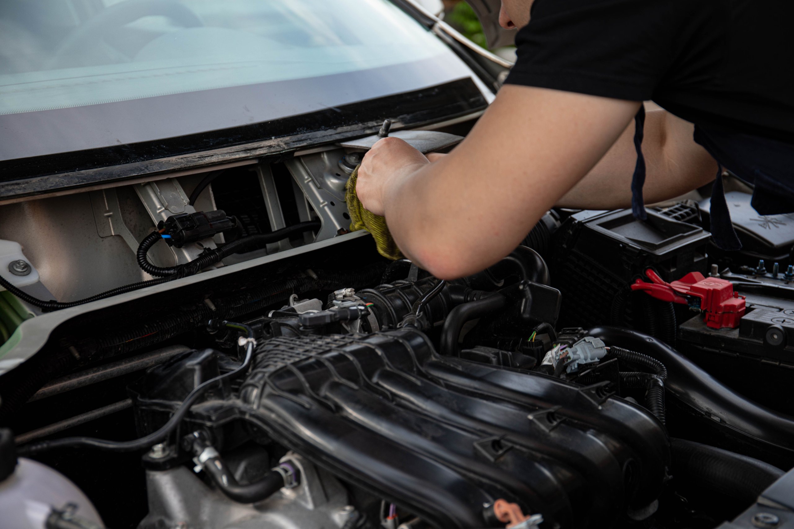 A mechanic is inspecting the belts and hoses under the hood of a vehicle, ensuring that essential components like the serpentine belt and cooling system parts are in top shape for optimal performance and safety. This routine vehicle maintenance helps prevent wear and tear, contributing to improved fuel efficiency and overall reliability.
