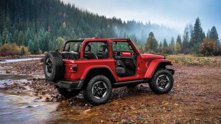 2020 Jeep Wrangler winnnipeg mb exterior side shot with firecracker red paint color and doors removed on wet earth and wood chips near a lake and forest with a foggy sky