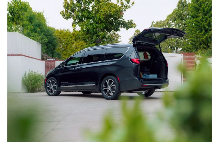 2021 Chrysler Pacifica exterior side rea shot by a brick and fence gate with trunk open for cargo loading