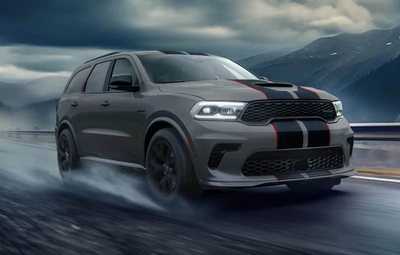 Grey Dodge Durango with sport stripes, front three-quarter, in motion on a mountain road