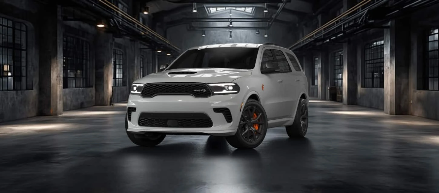 White Dodge Durango SRT parked in a dimly lit industrial warehouse, front three-quarter