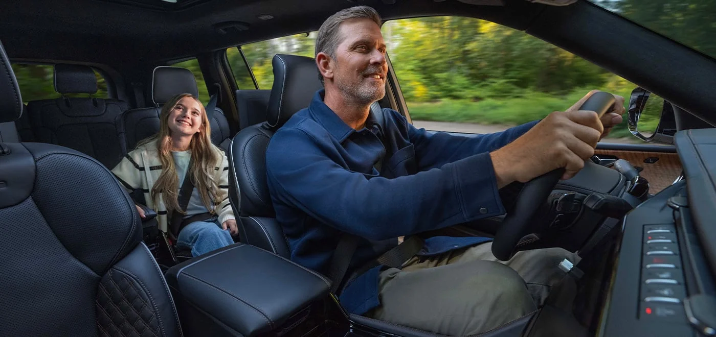 Jeep Grand Cherokee interior, a driver up front and a young passenger in the second-row seat