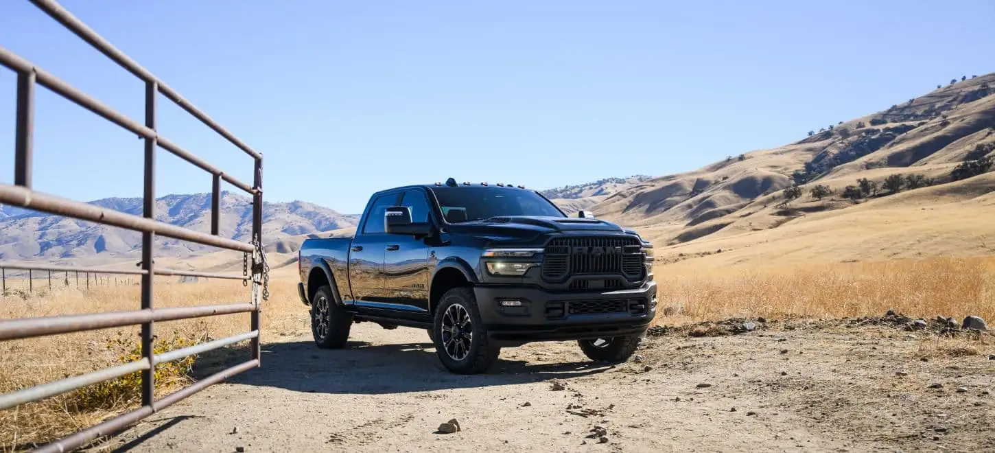 Black Ram 2500 heavy duty pickup parked by a metal ranch gate in open country