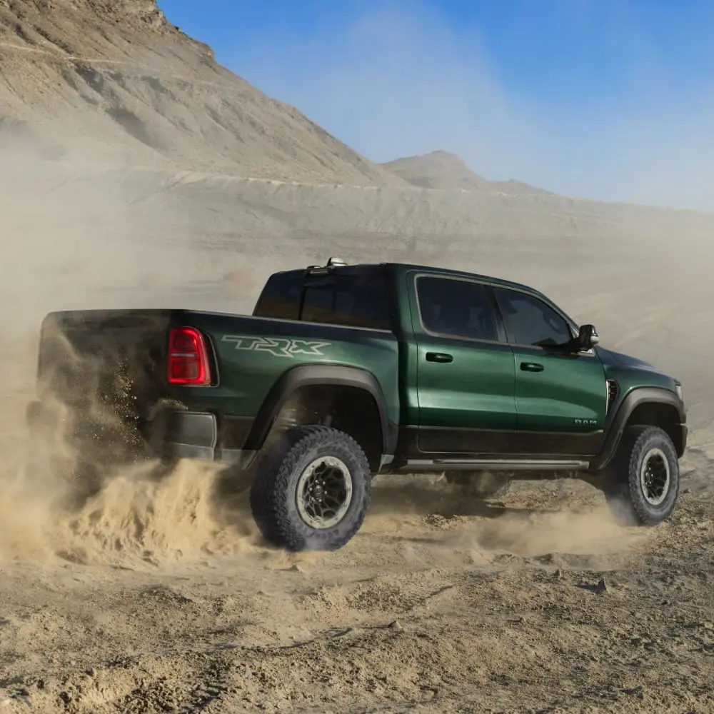 2027 Ram 1500 TRX in green kicking up dust through the desert at speed