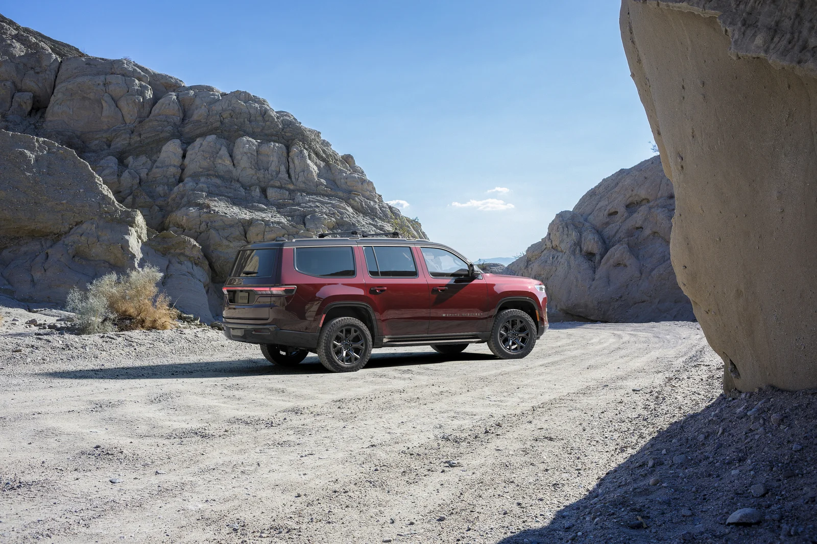 Dark red Jeep Grand Wagoneer rear three quarter parked in a rocky canyon