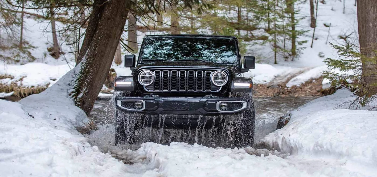 Jeep Wrangler two door with tan soft top crossing a shallow desert stream