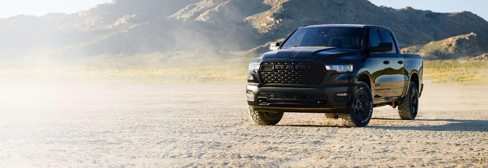 black Ram 1500 Warlock front three quarter parked on cracked desert ground