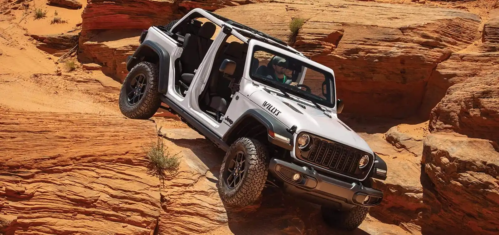 white 2026 Jeep Wrangler Willys 2 door with doors off descending a slickrock ledge