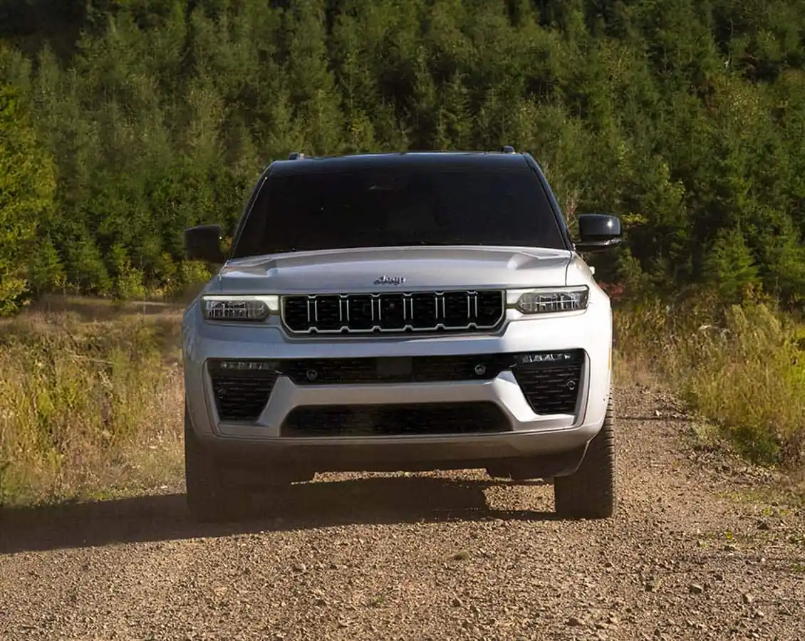 white Jeep Grand Cherokee front wheel and lower body on snow showing the Grand Cherokee badge