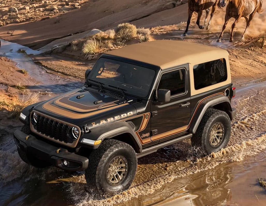Black Jeep Wrangler with hardtop crossing a snowy creek in a winter forest