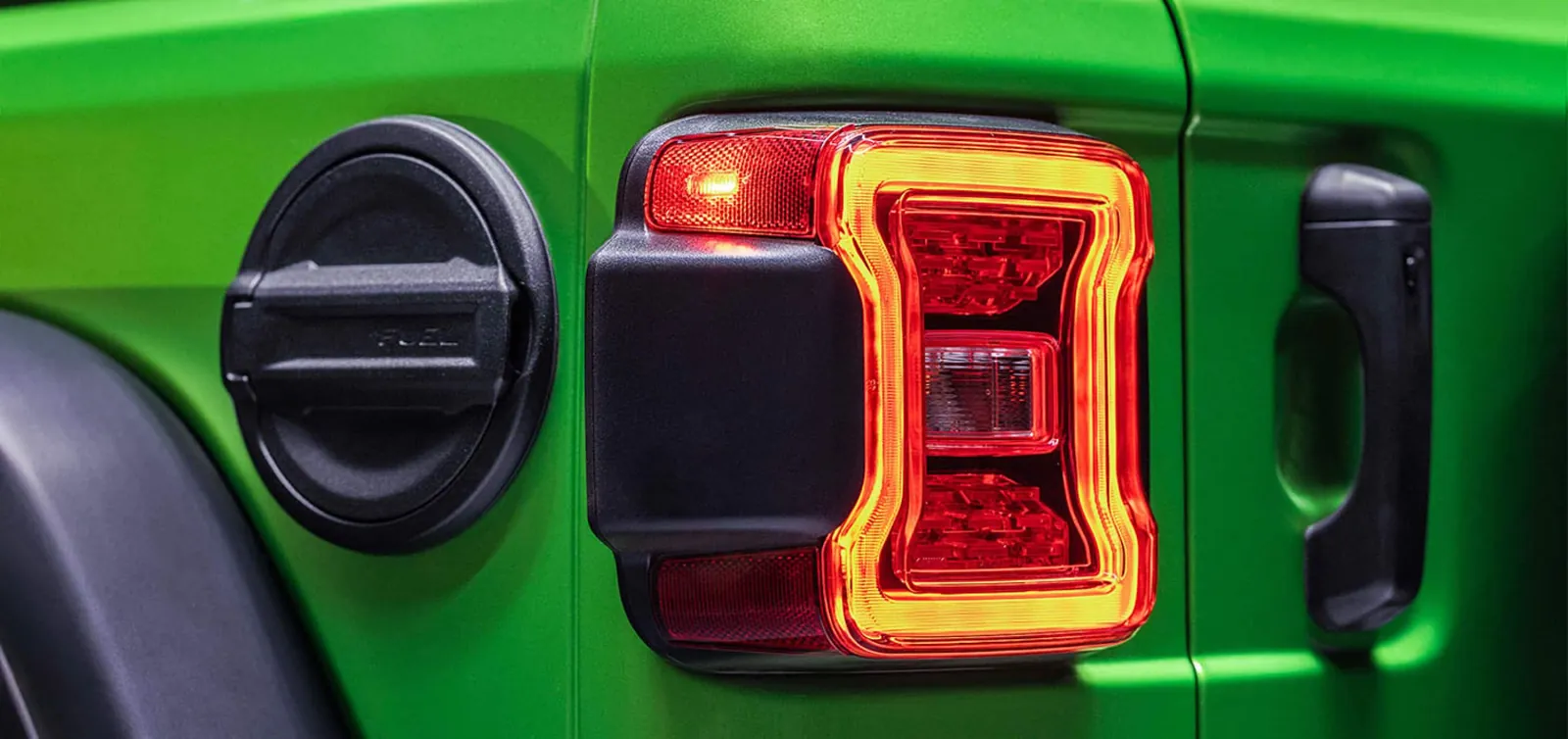 bright green Jeep Wrangler rear quarter with fuel filler door and lit tail lamp