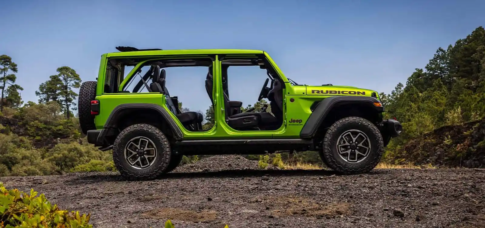 green 2026 Jeep Wrangler Rubicon four door side profile with doors off and top open