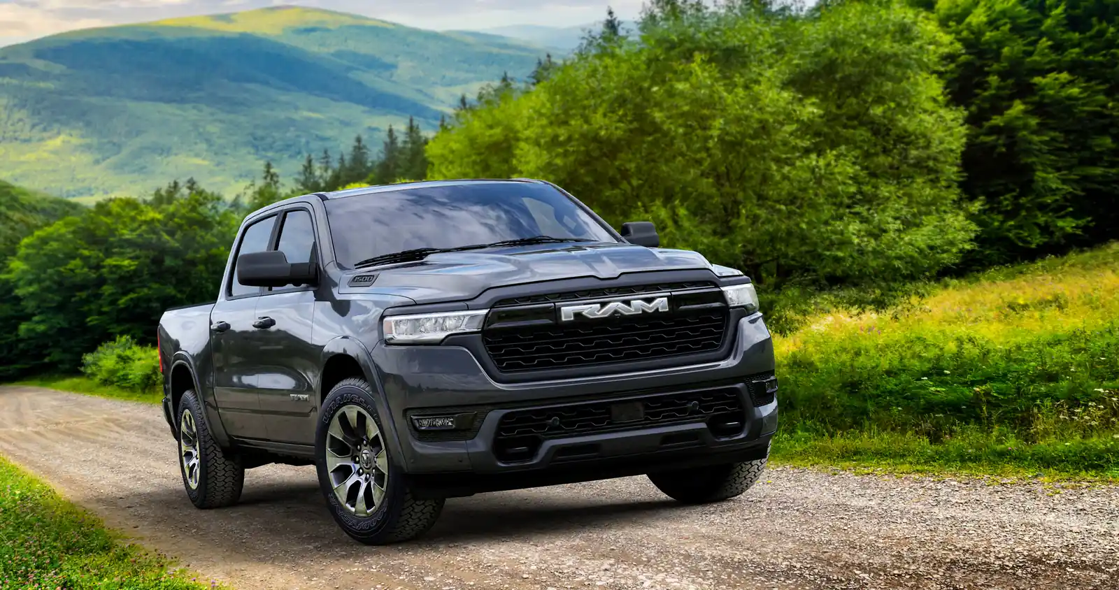 granite grey 2026 Ram 1500 parked on a gravel back road with green hills behind