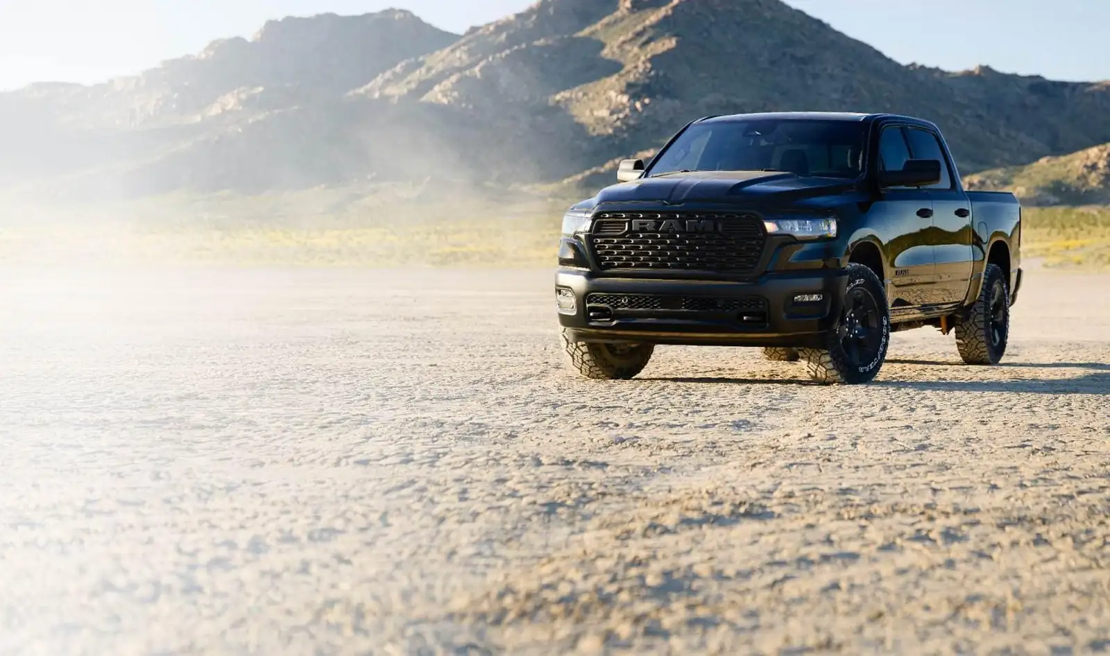 black 2026 Ram 1500 crew cab front three quarter view parked on an open flat