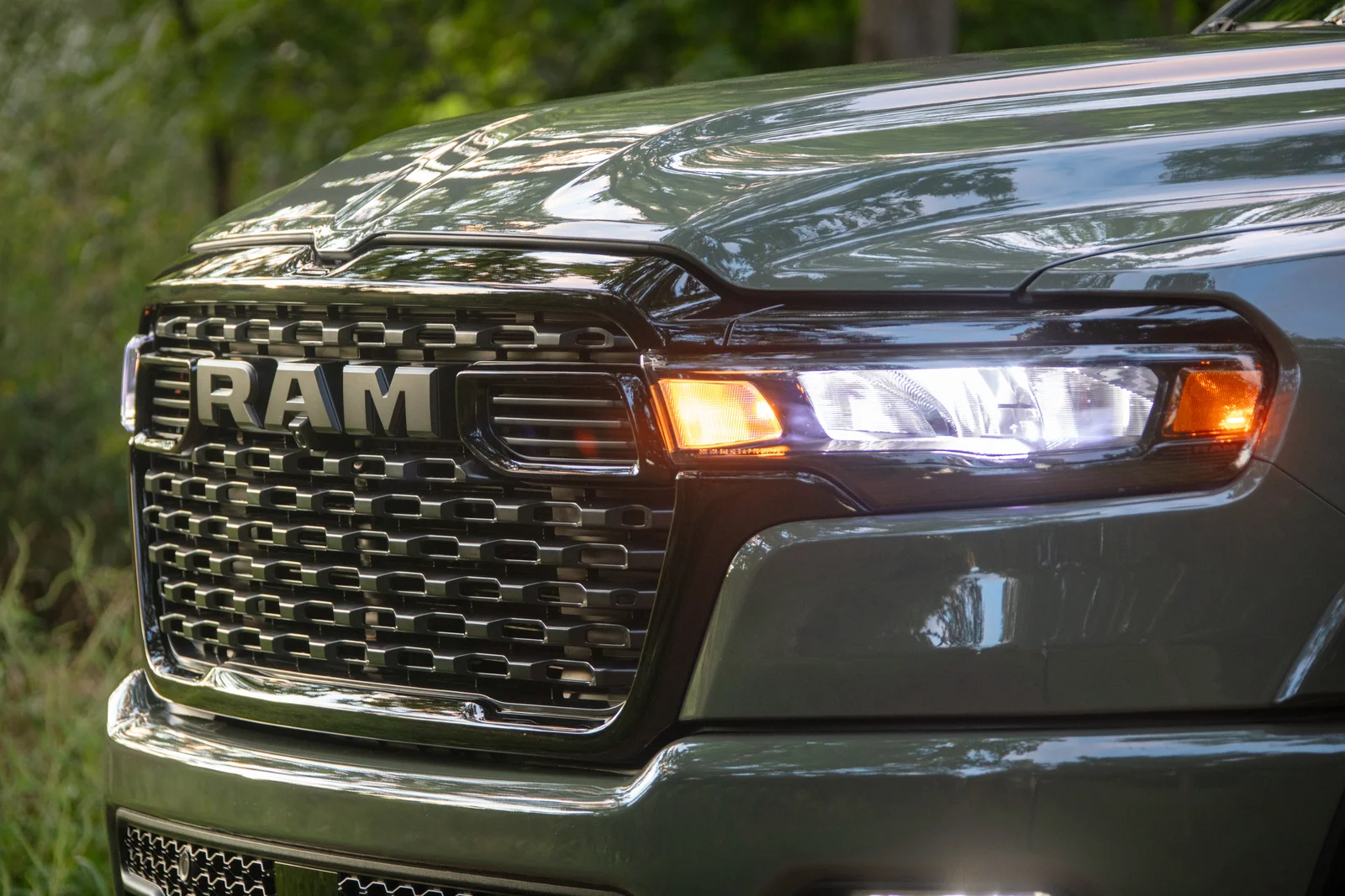 Ram 1500 front grille and lit headlamp detail during a lighting check