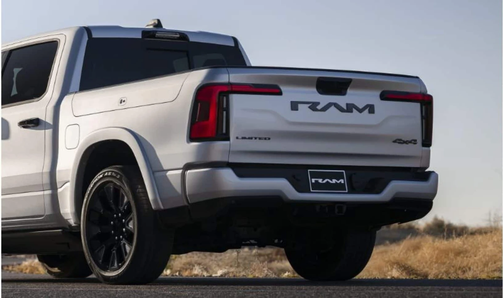 white Ram 1500 REV rear three quarter view showing the RAM tailgate and charge port door