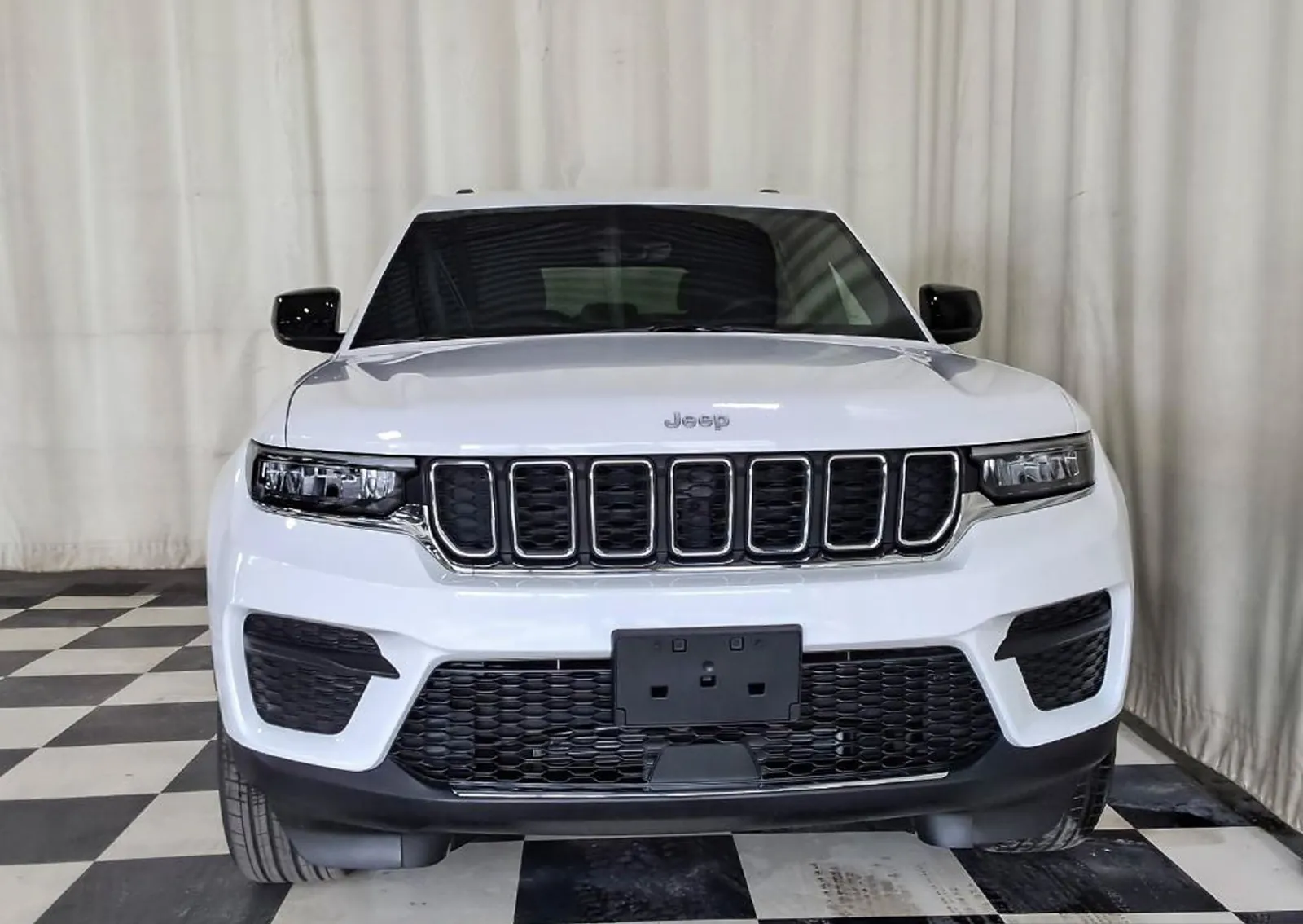 Bright White Jeep Grand Cherokee Laredo exterior in a clean studio setting