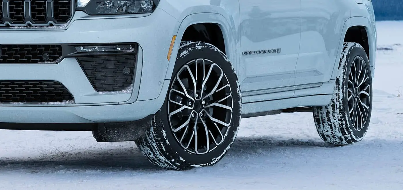 White 2026 Jeep Grand Cherokee front wheels pushing through deep snow