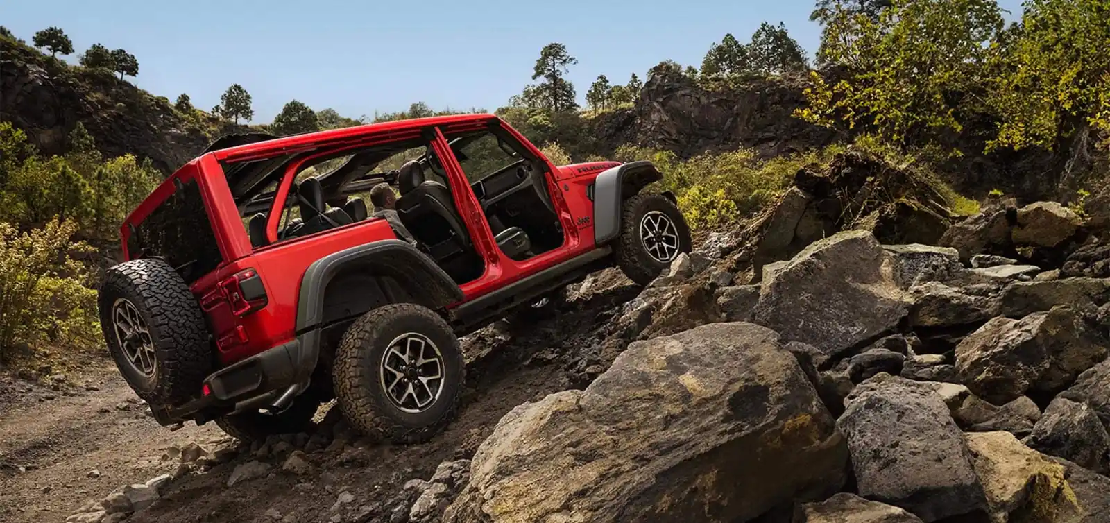 Red 2026 Jeep Wrangler Rubicon with doors off descending red slickrock