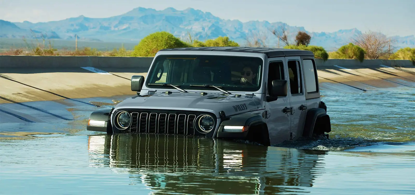 Grey 2026 Jeep Wrangler Willys fording deep water on a trail