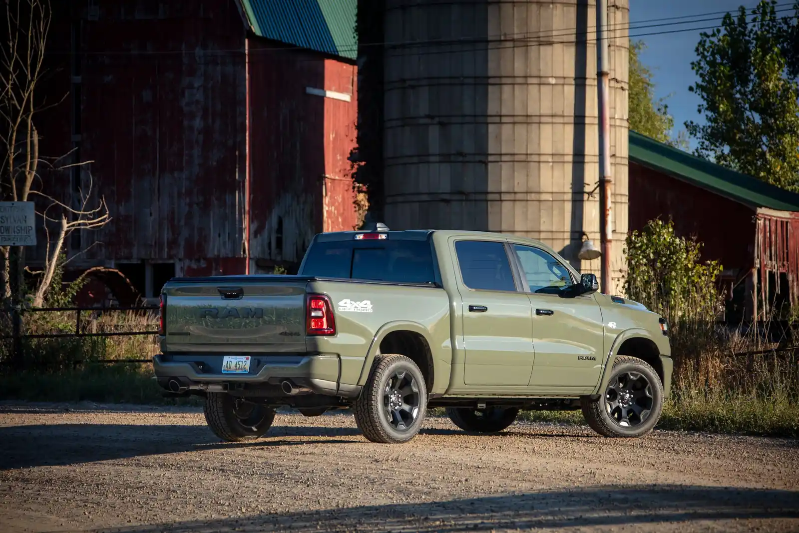 Green Ram 1500 Big Horn rear three quarter on gravel with a barn behind