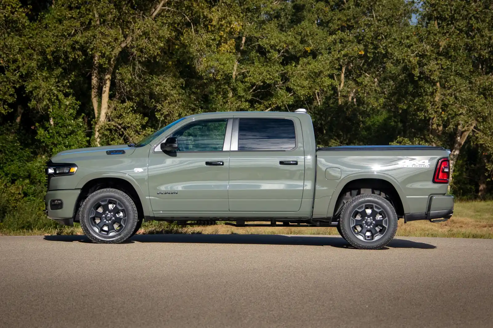 Green 2026 Ram 1500 Big Horn side profile against a summer tree line