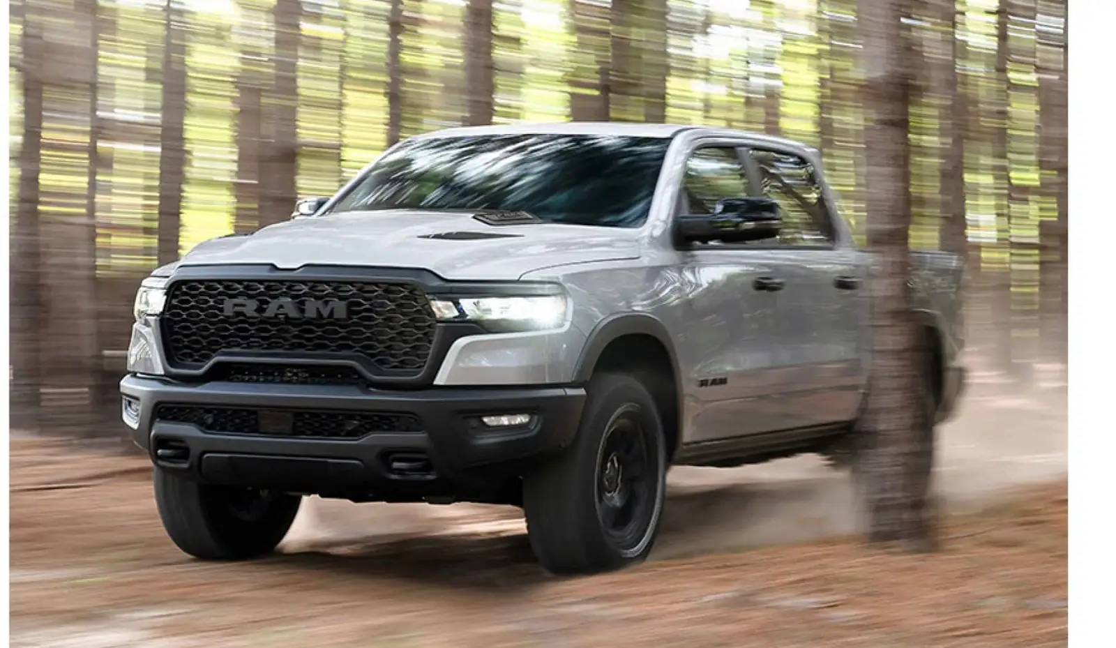 Silver Ram 1500 Rebel driving a dirt trail through tall timber
