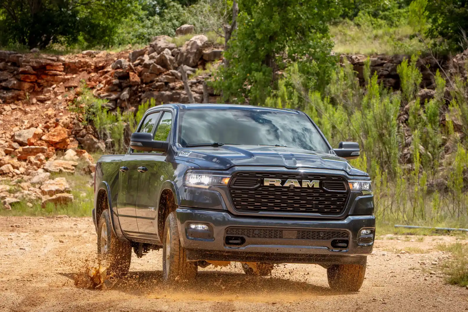 Grey Ram 1500 driving on a gravel two track with dust kicking off the tires