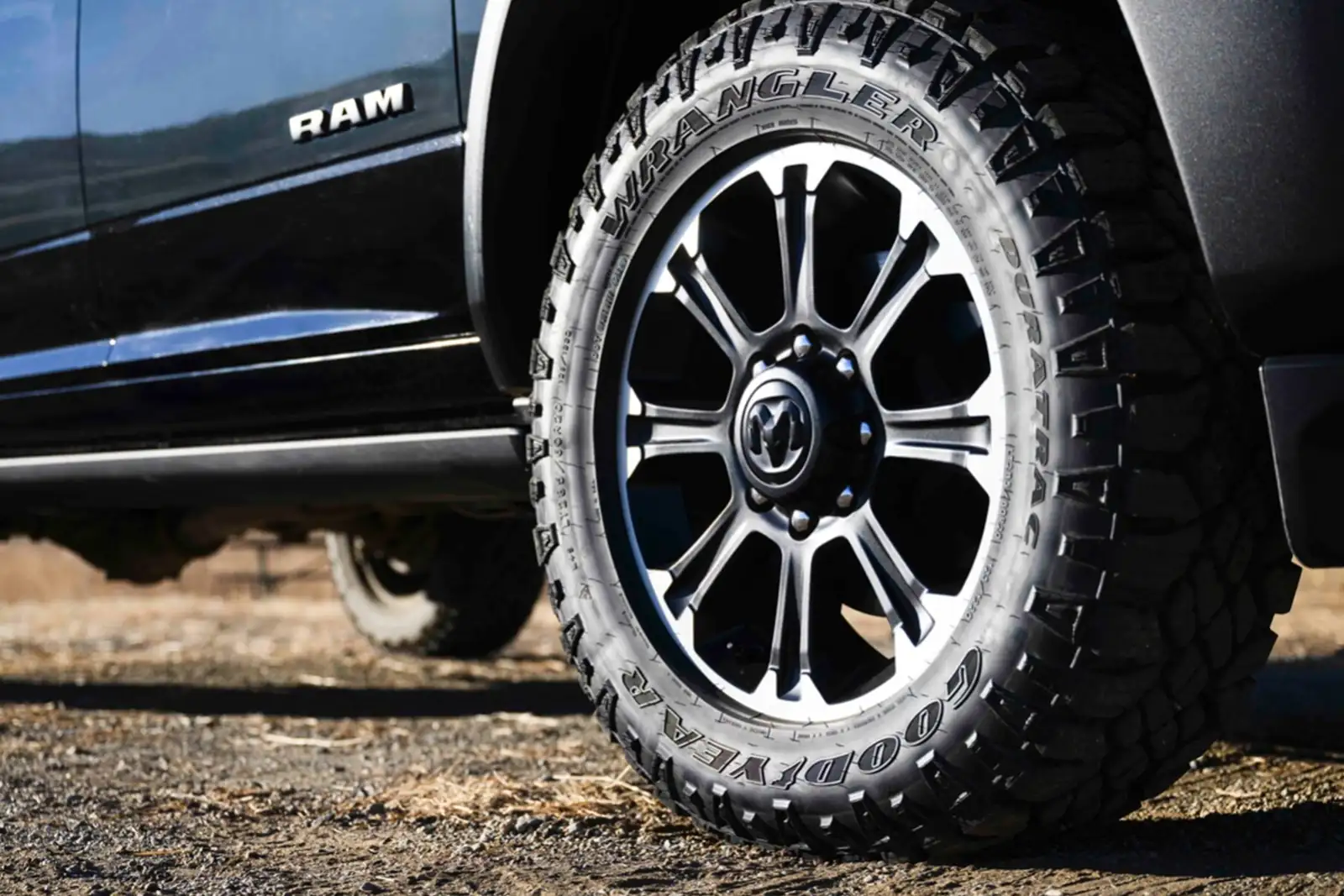 Ram 2500 all terrain tire and alloy wheel close up on gravel