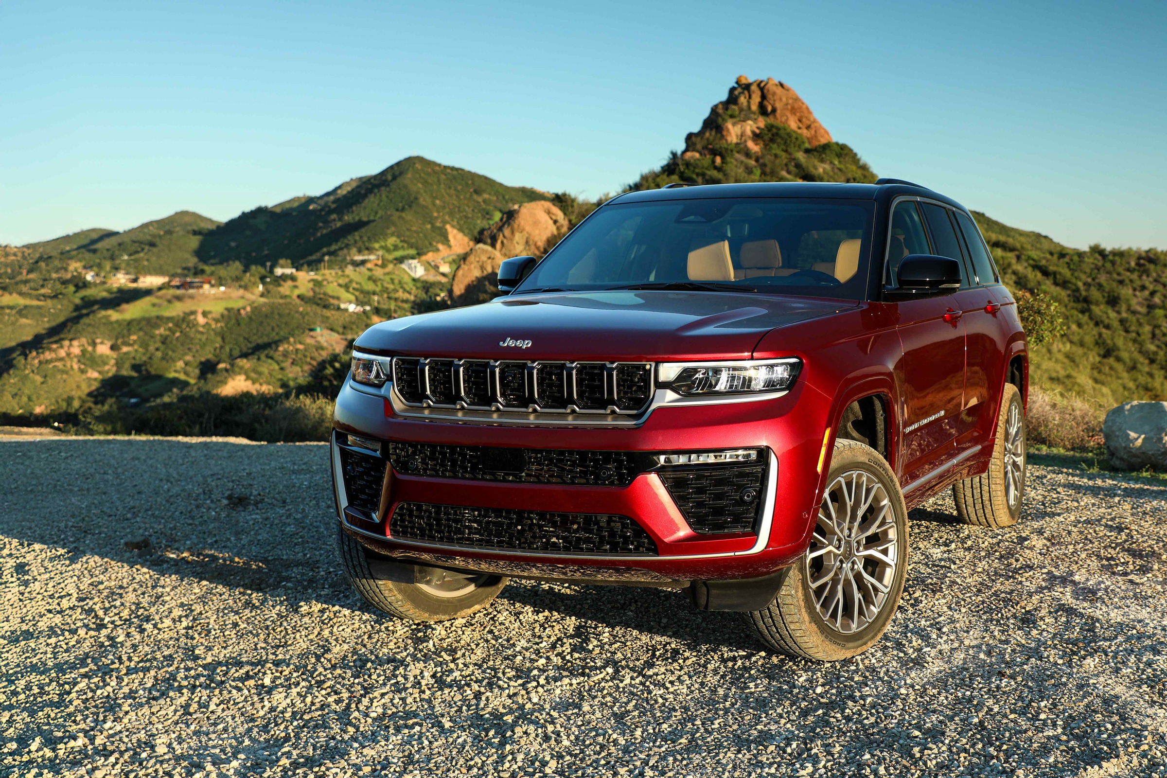 red Jeep Grand Cherokee front three quarter view on a gravel overlook