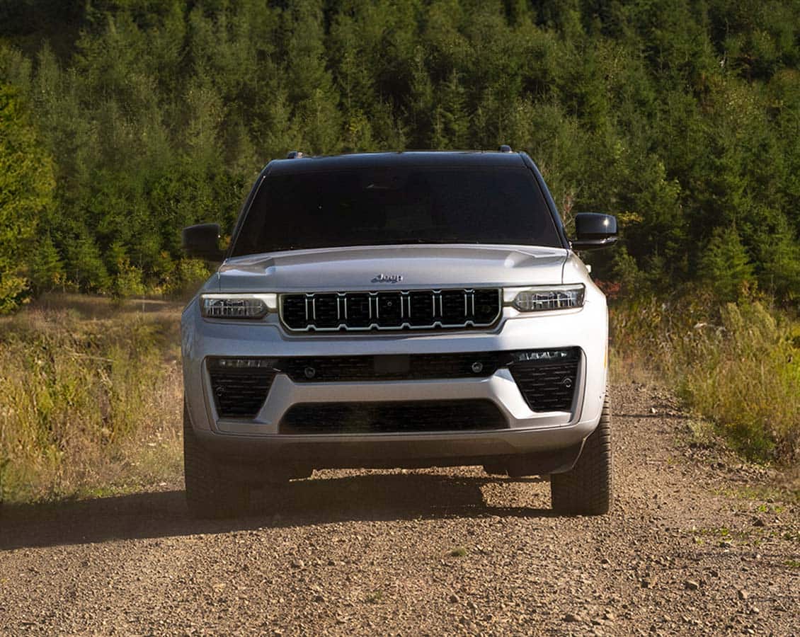 2026 Jeep Grand Cherokee in silver parked on a gravel forest road