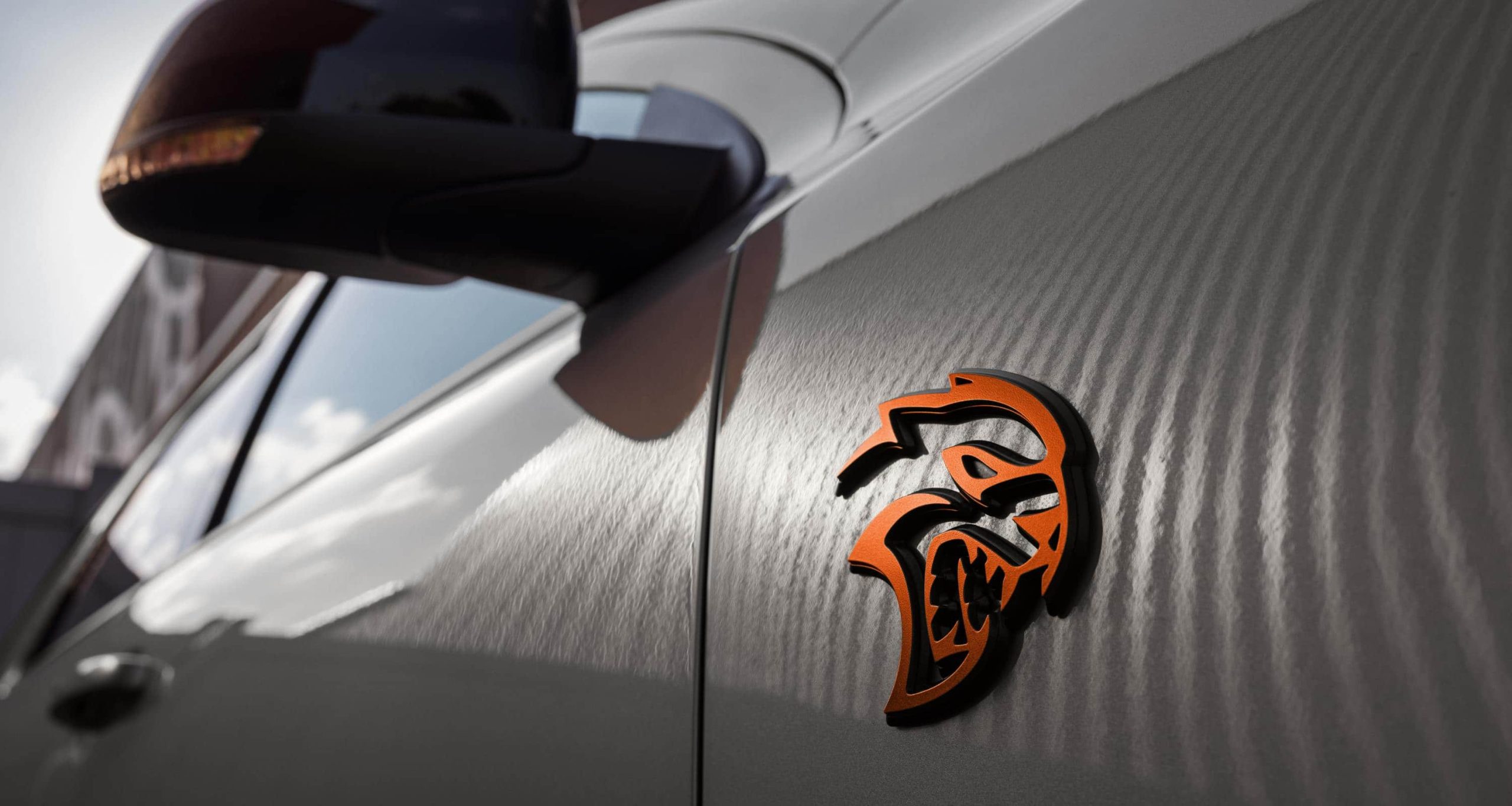 Orange Hellcat badge on the front fender of a grey Dodge Durango SRT Hellcat