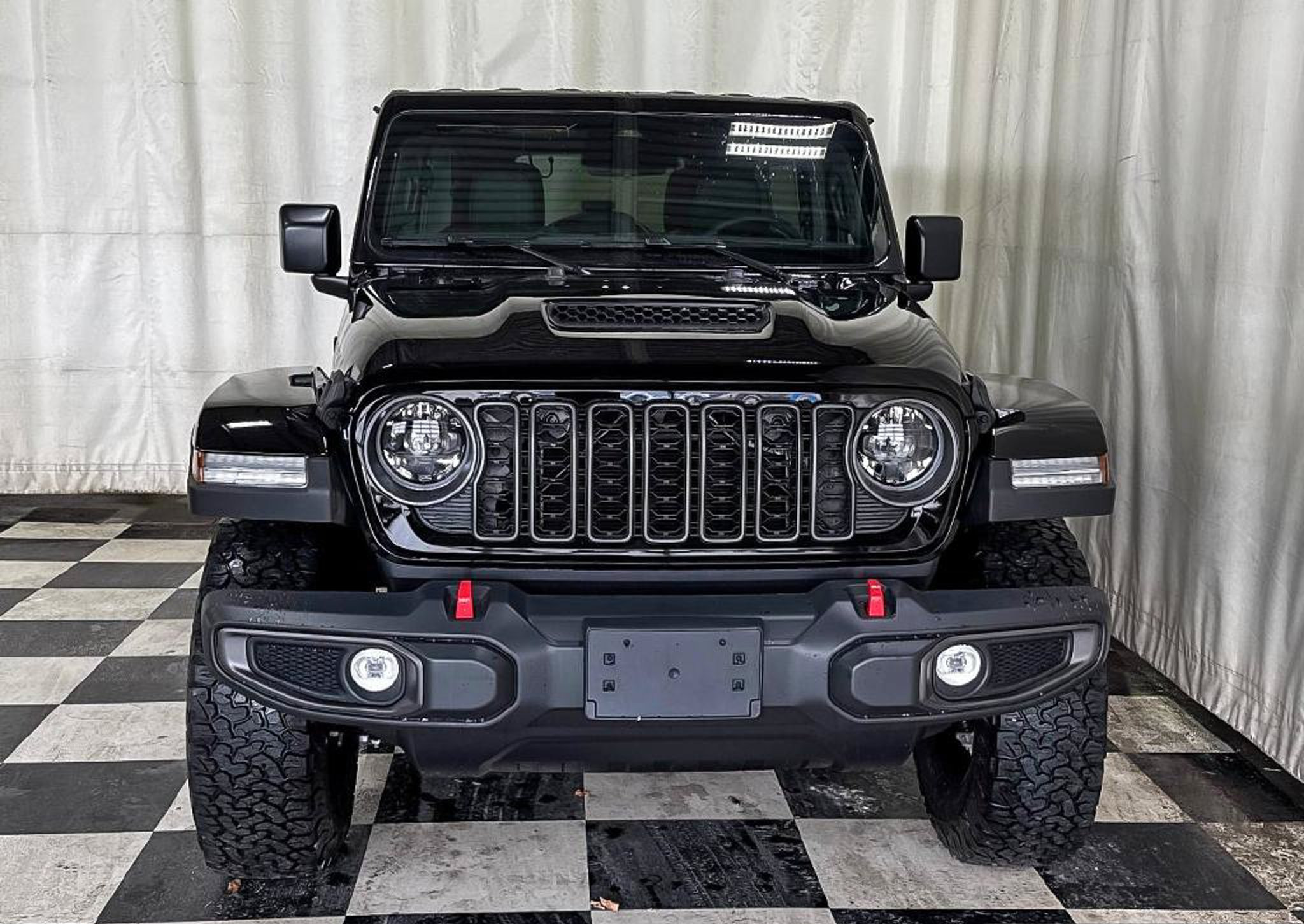 2027 Jeep Wrangler Rubicon, straight-on front view with the red tow hooks and off road tires, studio photo of a Dunn Ram Trucks unit